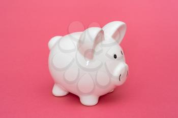 Economy or savings concept with white piggy-bank on pink background