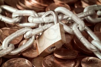 Pile of coins and a padlock with chain. Saving money concept.