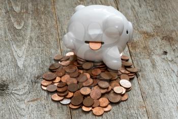 Coins spilling out of the piggy bank on the wooden background