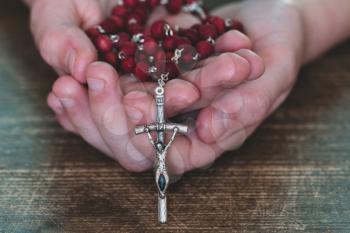 Close-up of little child hands holding  rosary. Child praying