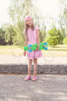 Child girl with penny skateboard on sunny summer day