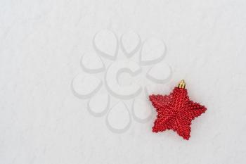 Christmas decoration red star lying on the fresh snow. Copy space.