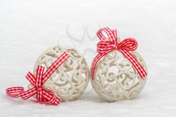 Two Christmas baubles with a red bows on the white fresh snow