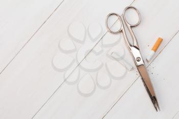 Scissors and broken cigarette on wooden background. Anti smoking or quit smoking concept.