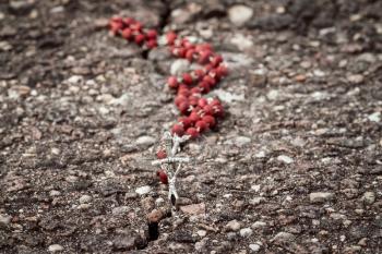 Catholic rosary in the crack of asphalt road