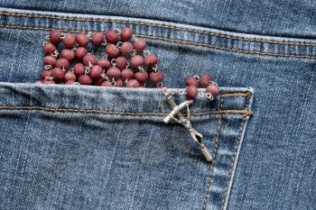 Catholic rosary in the back pocket of the denim jeans
