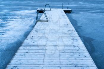 Snow covered wooden bridge on the frozen lake