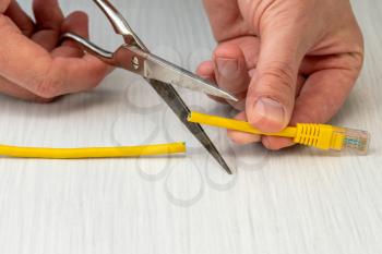 Internet censor cutting a yellow network cable with scissors.Restricted internet access concept 