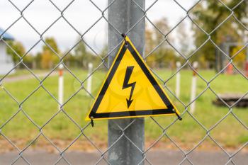 Warning sign on boundary fence of electricity substation