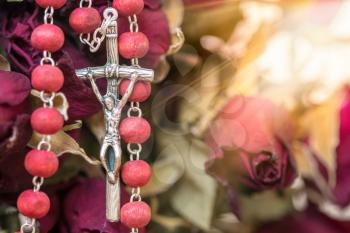 Catholic rosary and dry roses, close-up view. Faith and hope concept.
