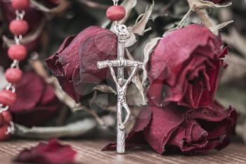 Catholic rosary and dry roses, close-up view. Faith and spirituality concept.