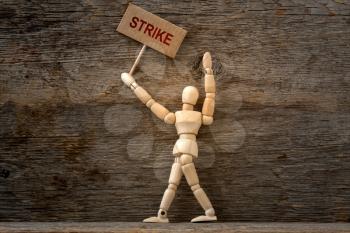 Wooden mannequin holding protest banner on job strike.