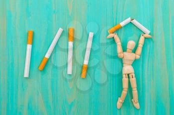 Quitting smoking - wooden man crushing cigarettes