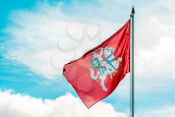 Historical Lithuanian flag, coat of arms of Lithuania, consisting of an armour-clad knight on horseback holding a sword and shield, is also known as Vytis, waving in the wind against sky background 