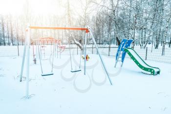 Empty children's playground in winter after snowing