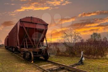 Railway containers with bulk materials. The locomotive pulls a large freight train. Sunset time.