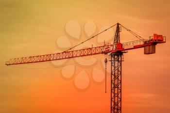 Tower crane on building construction site at sunrise.