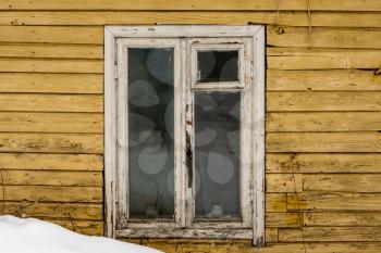 White wooden window on a background of an old yellow wooden wall. Near a winter snowdrift. 