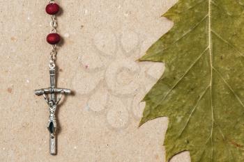 Close-up view of catholic rosary and dry green leaf