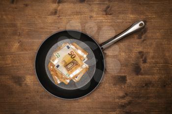 Concept or metaphor for business success, prosper restaurant or luxury, expensive cooking. Euro bills in a frying pan.