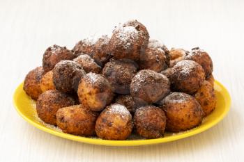 Small balls of freshly baked homemade cottage cheese doughnuts in a plate on a wooden background.