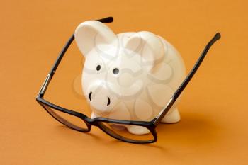 Piggy bank and eyeglasses on the yellow background. Conceptual image.