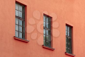 A row of old windows on the red concrete wall 