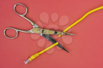 Scissors cutting the yellow network cable. Prohibit and restrict access to the internet, limit internet connection concepts. 