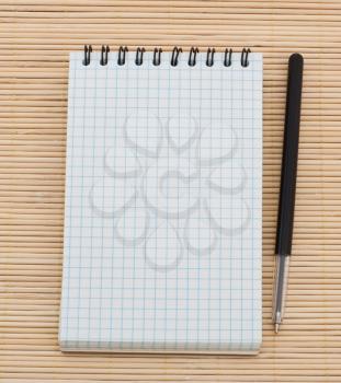 Empty notebook and pen on wooden background