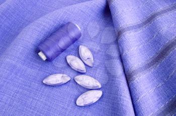 Threads and buttons on the lilac monotonous and striped fabric