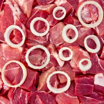 The rings of white onion on a background of red pieces of meat (texture)