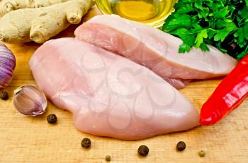 Chicken breast, vegetable oil in a bottle, red hot pepper, ginger, garlic on a wooden board