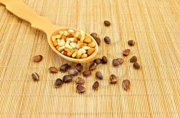 Cedar nuts, cedar nut kernels in a wooden spoon on a bamboo mat