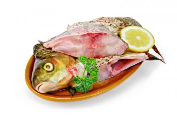 Bream whole peeled and cut into chunks in a clay plate, parsley, lemon isolated on a white background