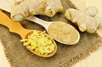 Two wooden spoons of powder and grated ginger, ginger root on a napkin on a burlap background wooden board