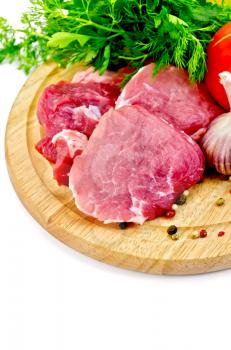 Cuts of meat, garlic, tomatoes, parsley, dill on a round wooden board isolated on white background