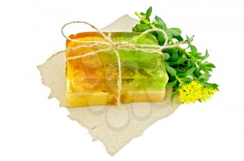 Two pieces of homemade soap, tied with twine with Rhodiola rosea flowers on a piece of paper isolated on white background