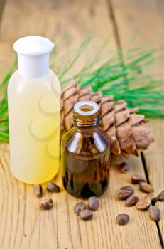 Cedar oil and lotion bottles, cedar cone, cedar nuts on the background of wooden boards
