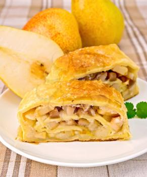 Strudel with pears in white plate, pears, against a linen tablecloth