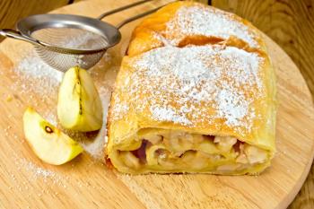 Apple strudel with icing sugar, strainer on a wooden boards background