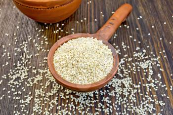 Sesame seeds in a clay ladle on a background of wooden boards