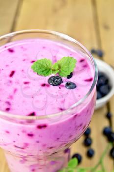 Milkshake with blueberries and mint in a glassful on a wooden plank background