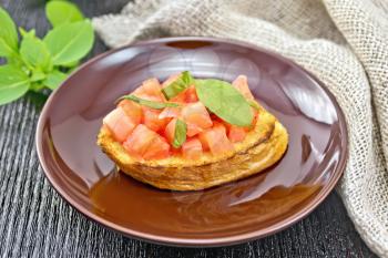 Bruschetta with tomatoes and basil in a plate, napkin on a wooden board background