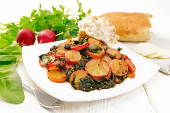 Radish stewed with spinach and spices in a plate, cheese and bread, towel against light wooden board background
