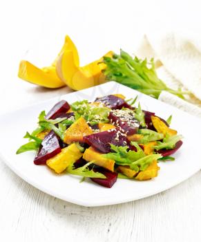 Salad of baked pumpkin, boiled beets, arugula, seasoned with vinegar, spices, orange juice and vegetable oil in a plate on background of light wooden board