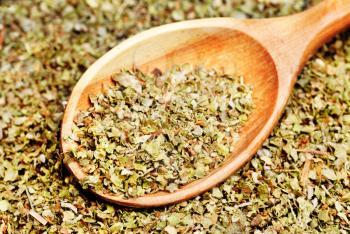 Dried marjoram spice and wood spoon as food background 


