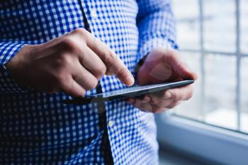 The man uses a tablet PC. Modern gadget in hand.