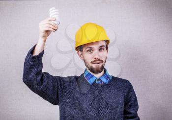 Young builder holding energy saving bulb