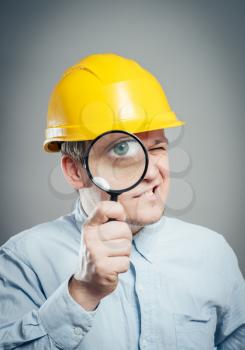 Asian engineer man wear hardhat  hold a magnifying glass focus on the glass isolated 