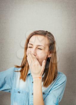 A close-up portrait of an attractive young female with yawn gesture